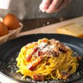 delicious pasta carbonara on black plate.
